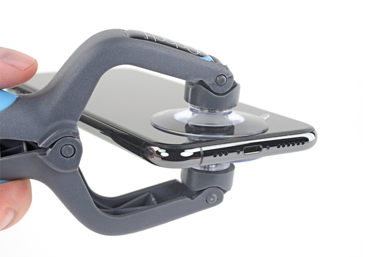 Egy iPhone kijelzőjének ragasztásához használt ragasztóanyag szárítása, speciális csíptető szerszám segítségével.