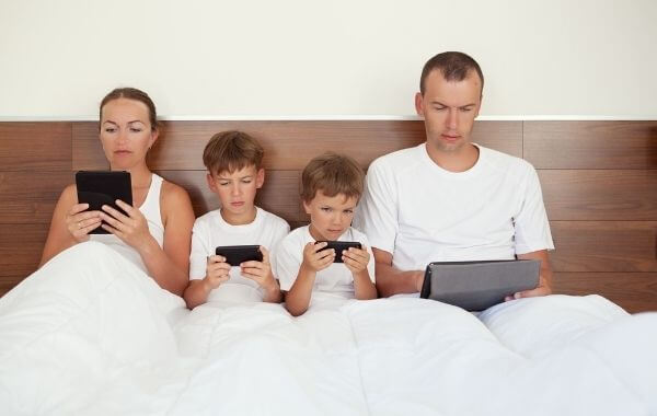 Egy 4 tagú család filemt néz az ágyban