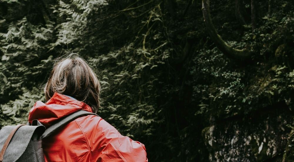 Egy nő piros esőkabátban túrázás közben