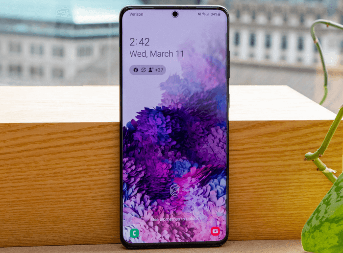 Egy Samsung Galaxy S20 Plus állítva elhelyezve egy ablakban, egy növény mellett.